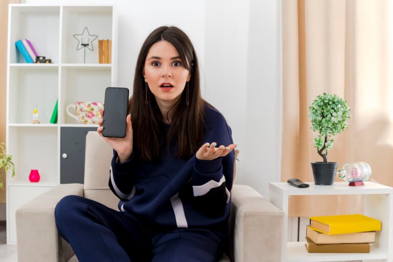 impressed young pretty caucasian girl sitting on armchair in designed living room showing mobile phone to camera looking at camera and showing empty hand SSUCv3H4sIAAAAAAAACpyRz27DIAzG75P2DhHnRgr52+xVqh0cYAkqhQrIpqnqu89AqDjvhn+2P/szj/e3qiILOMnIR/UIEcZSqd15C14ajbg5HdwKzYUtieDSGytBlXABzzYNN4FQ70oF/IxJ4jz43QkXhh2IgRcraiT4kkgbXVJc5URMYgemCDkVzO1LZBkl8X91psdndgOr0Ow3LlwYsUIJSEYuqZRcf7ywt9Ia7FyawtW3YaBCQVco3a1kUq9Fm/FbvHJuY2bX3oYVXpsTZcwdFhVO/IWaIvMNnMNynnkxiOGfmlsxRxsfDRyqhONPhJB2bT+389Q0Uzv19NyPR0H6vU2iTlwnC2HMrpKX1mXYgHDKO9Gch3rox6Hu4dzUM+VjTQfasmbg3UhHPPzzDwAA//8DANbPityHAgAA