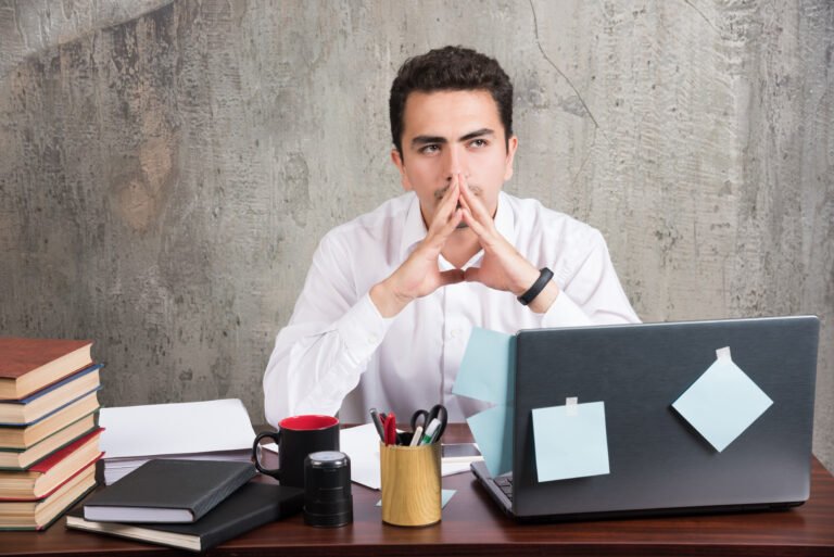 Tired employee thinking about work at the office desk. High quality photo